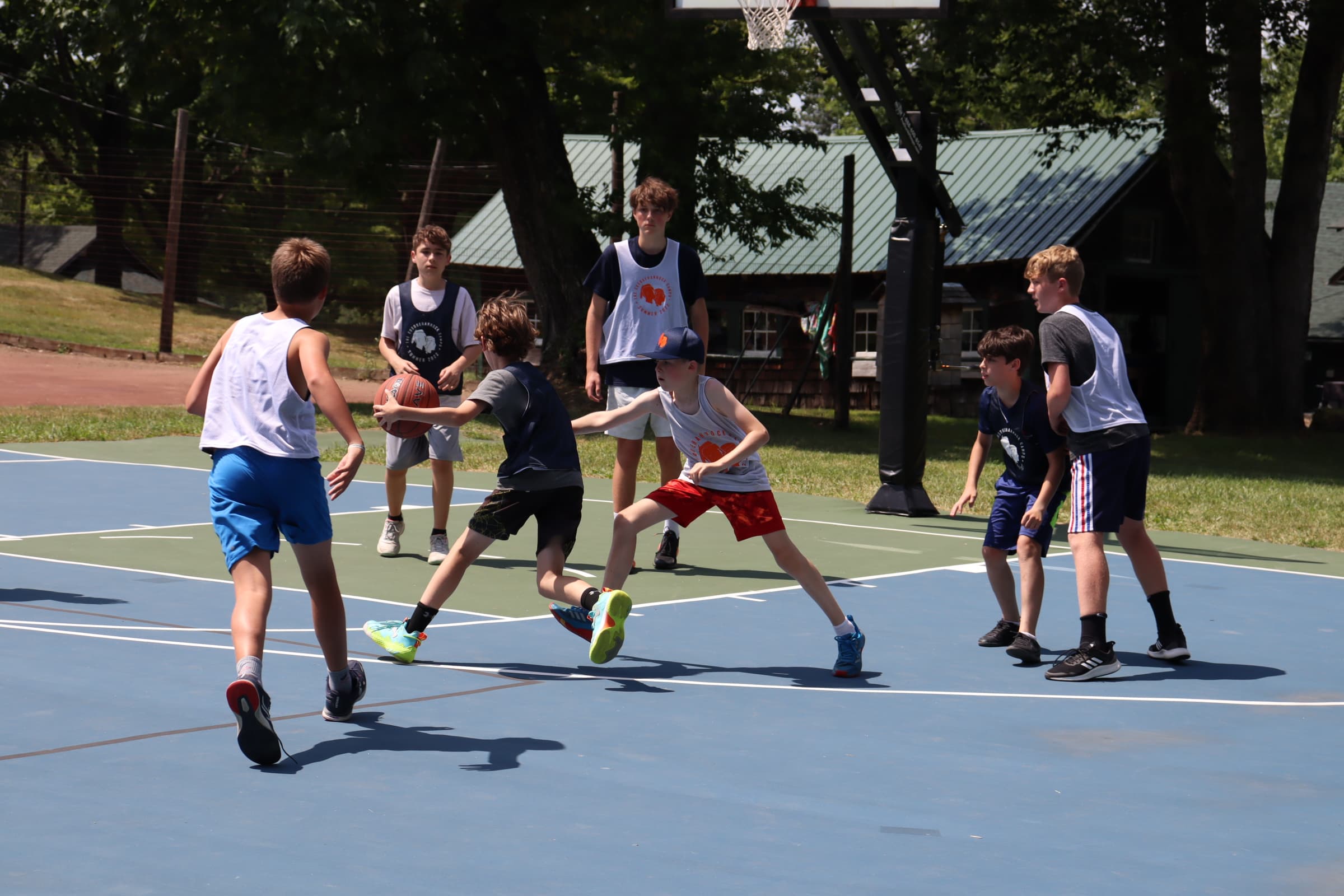 Boys playing basketball on outdoor court at camp
